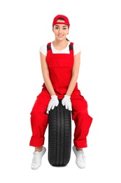 Female mechanic in uniform with car tire on white background