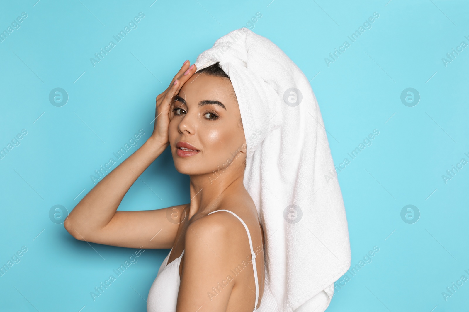 Photo of Beautiful young woman with towel on head against light blue background