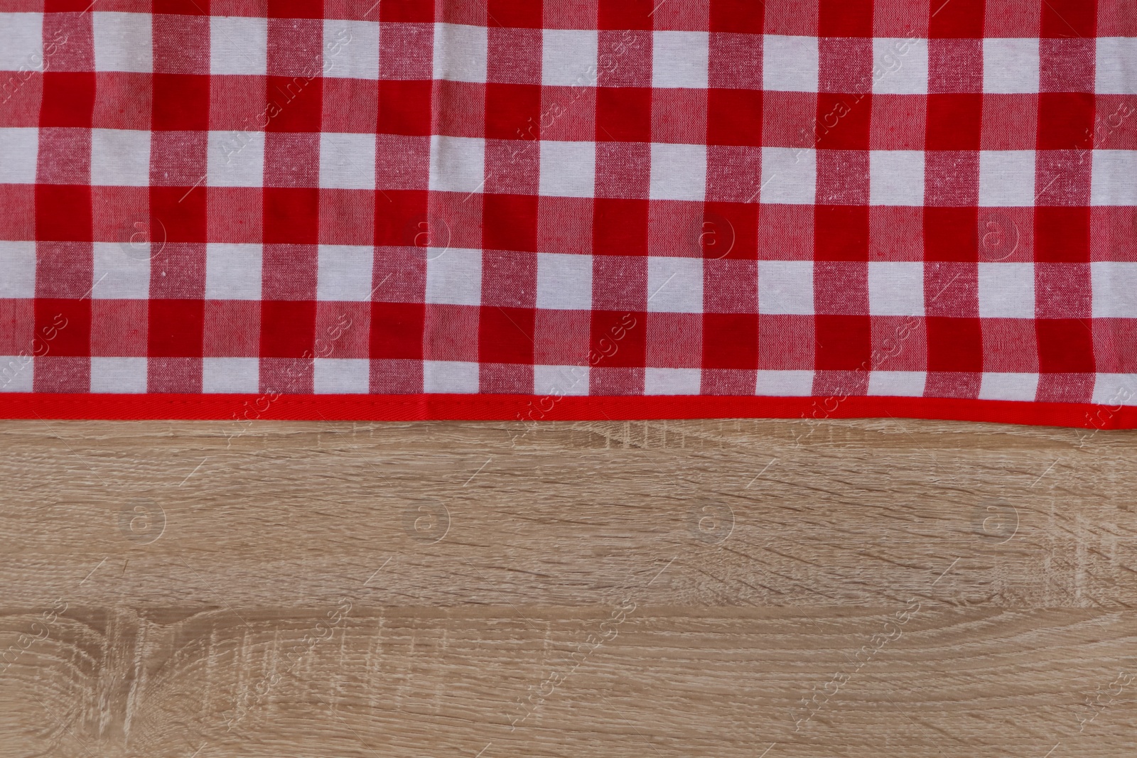 Photo of Checkered picnic cloth on wooden table, top view. Space for text