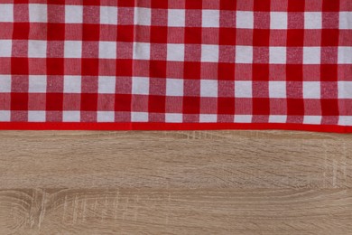 Photo of Checkered picnic cloth on wooden table, top view. Space for text