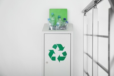 Many used plastic bottles in metal bin indoors, space for text. Recycling problem