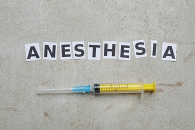Word Anesthesia and syringe on light table, flat lay