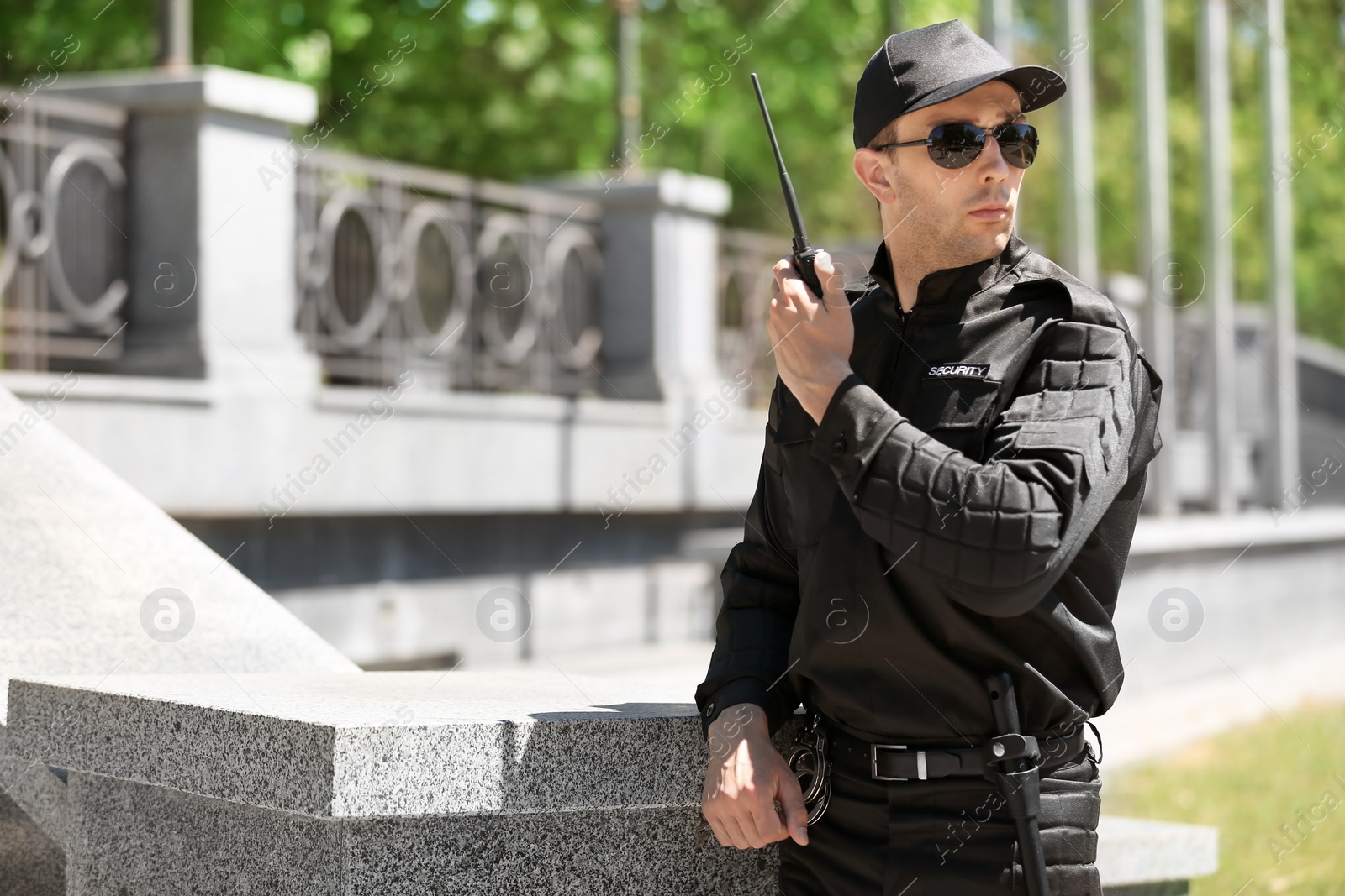 Photo of Male security guard using portable radio transmitter outdoors