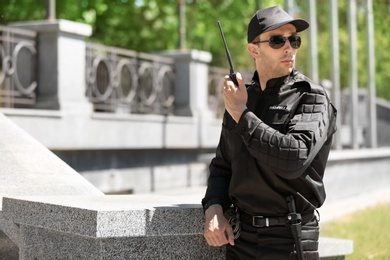 Male security guard using portable radio transmitter outdoors