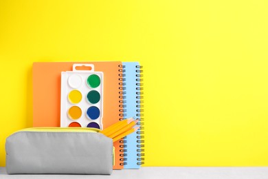 Photo of Different school stationery on white table against yellow background, space for text. Back to school