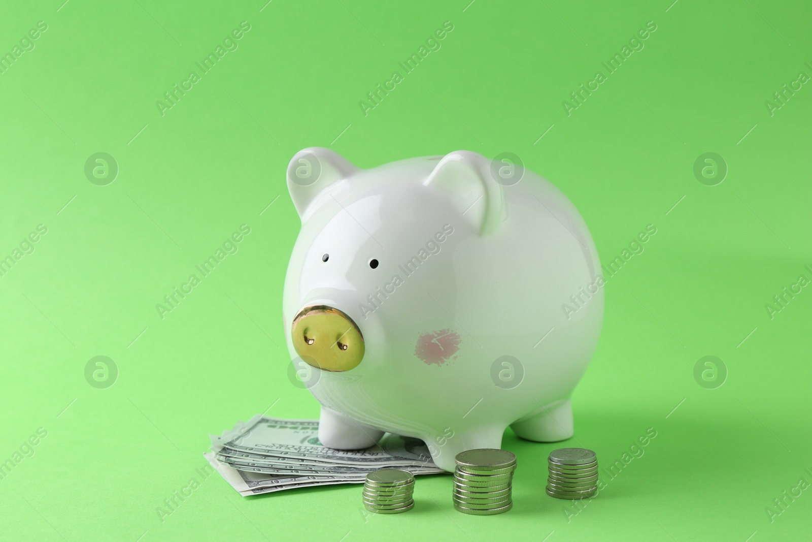 Photo of Financial savings. Piggy bank, dollar banknotes and stacked coins on green background