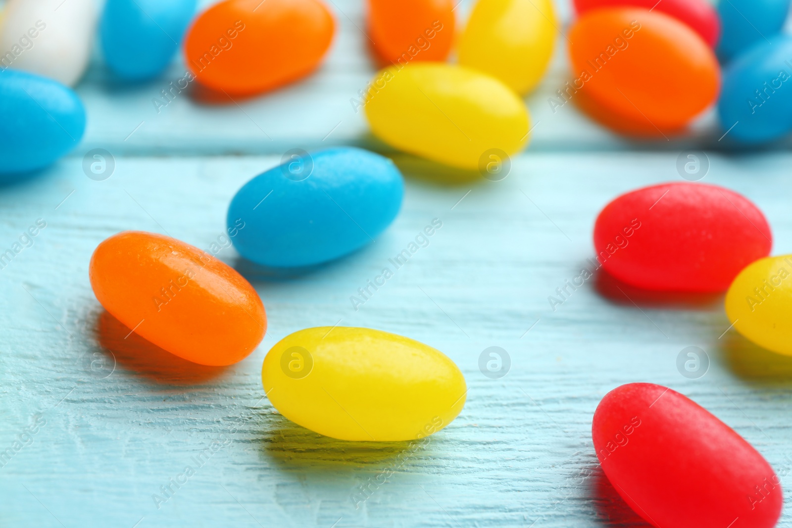 Photo of Colorful jelly beans on light blue wooden background, closeup