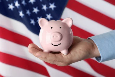 Photo of Woman holding piggy bank against American flag, closeup
