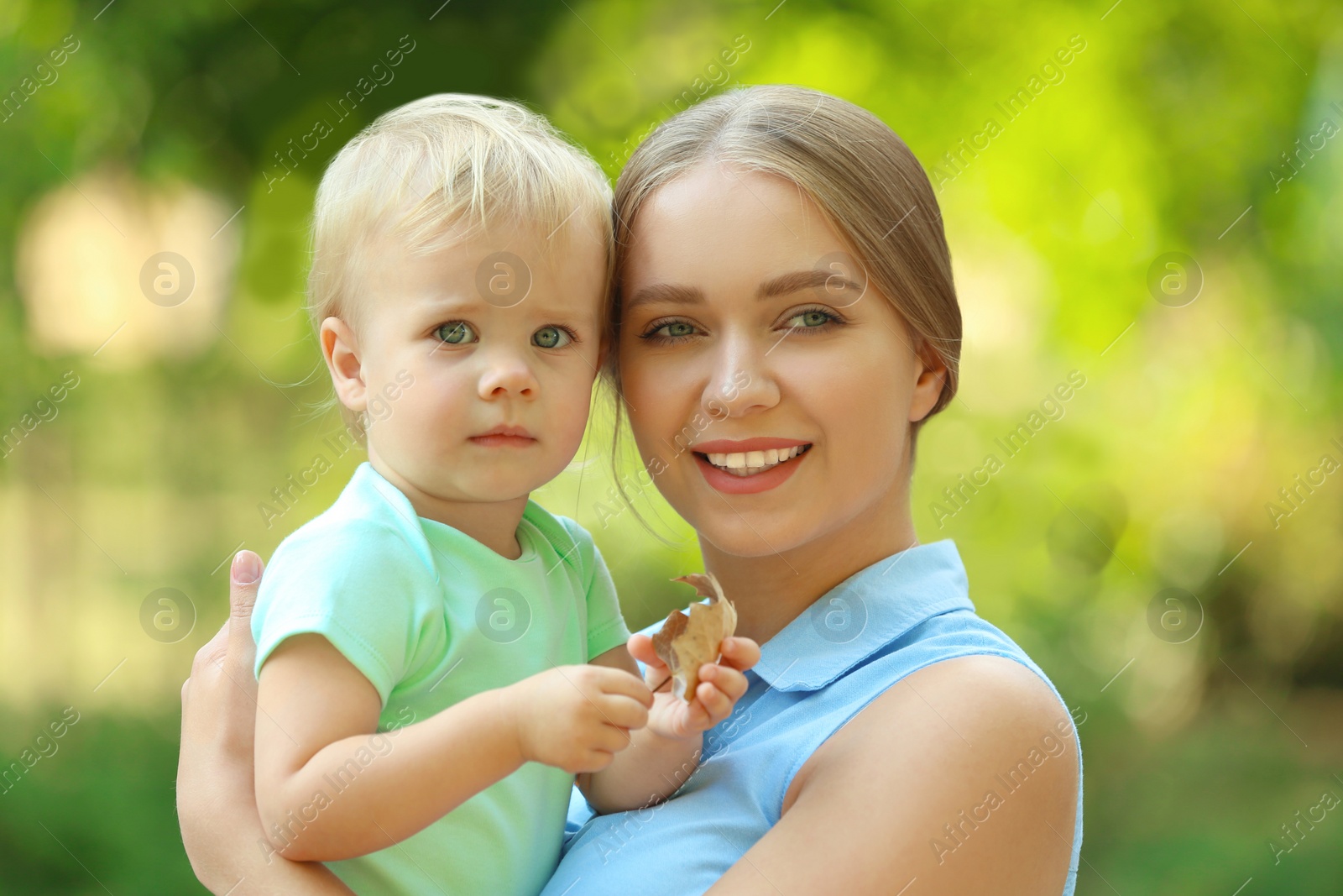 Photo of Young mother with her cute child in green park