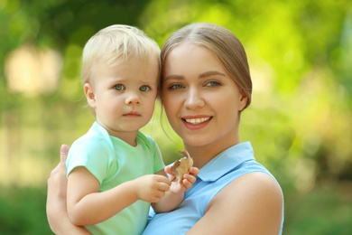 Young mother with her cute child in green park