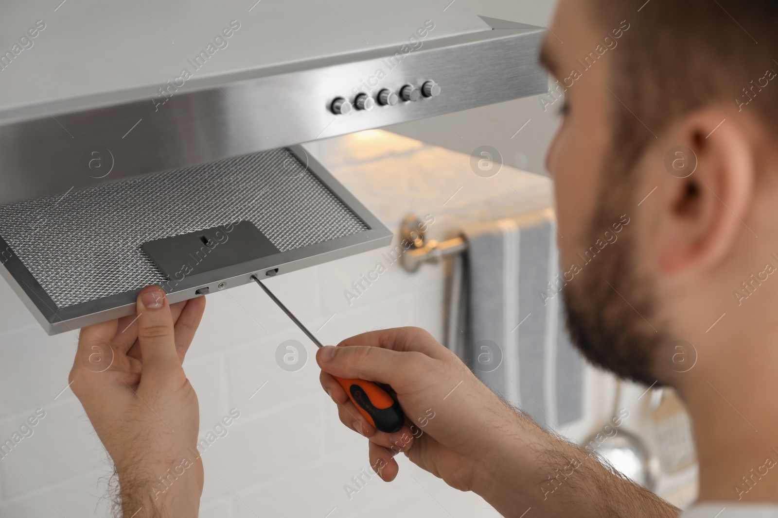 Photo of Worker repairing modern cooker hood indoors, closeup