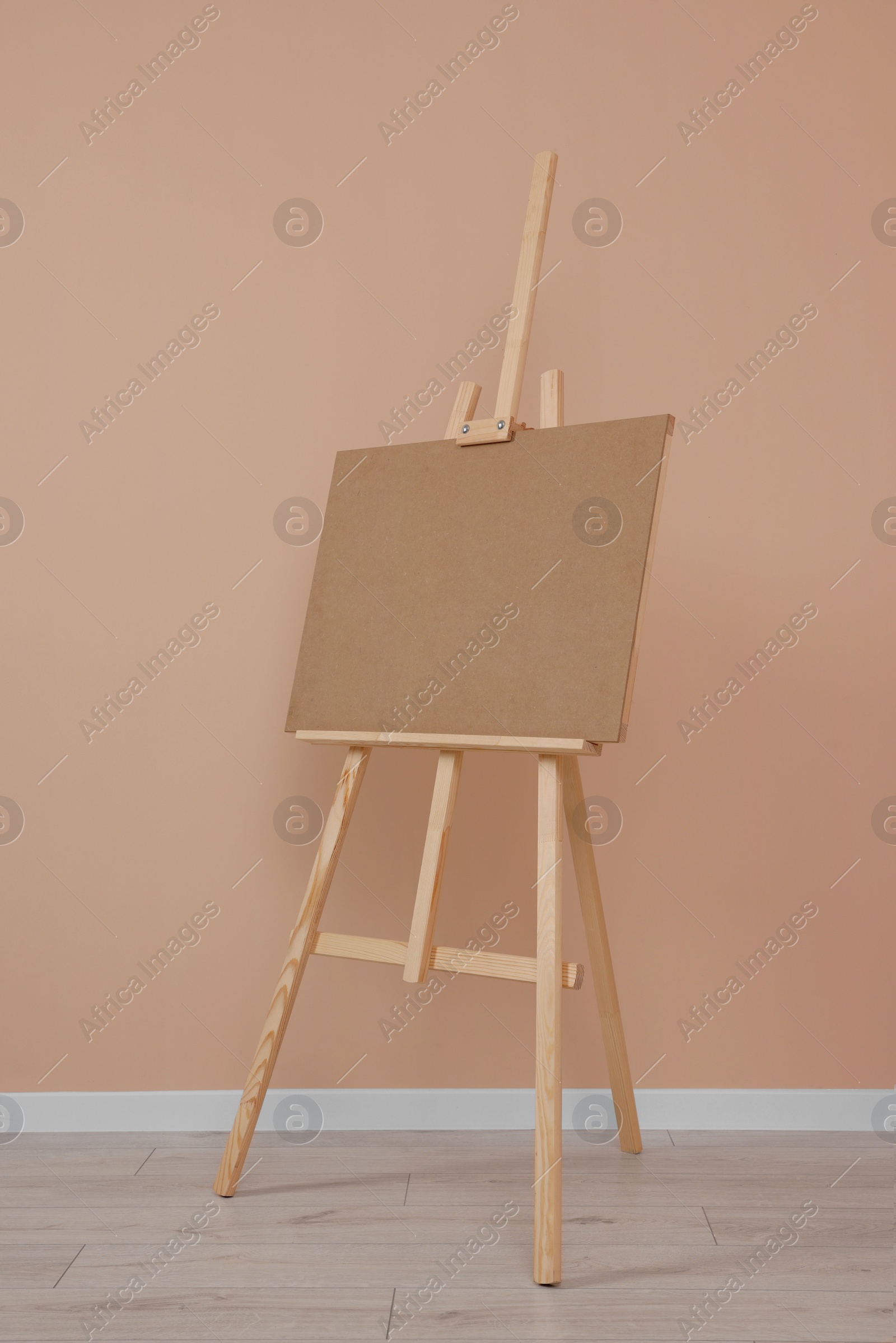 Photo of Wooden easel with blank board near beige wall indoors