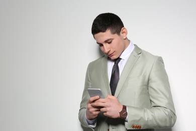 Photo of Portrait of young businessman using smartphone on light background. Space for text