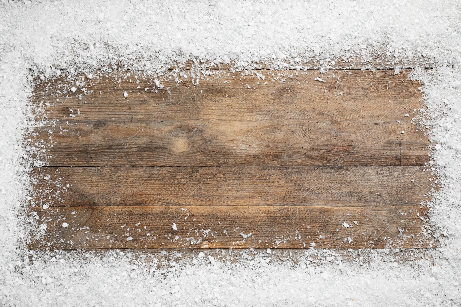 Photo of Frame made of snow on wooden background, top view with space for text. Christmas season