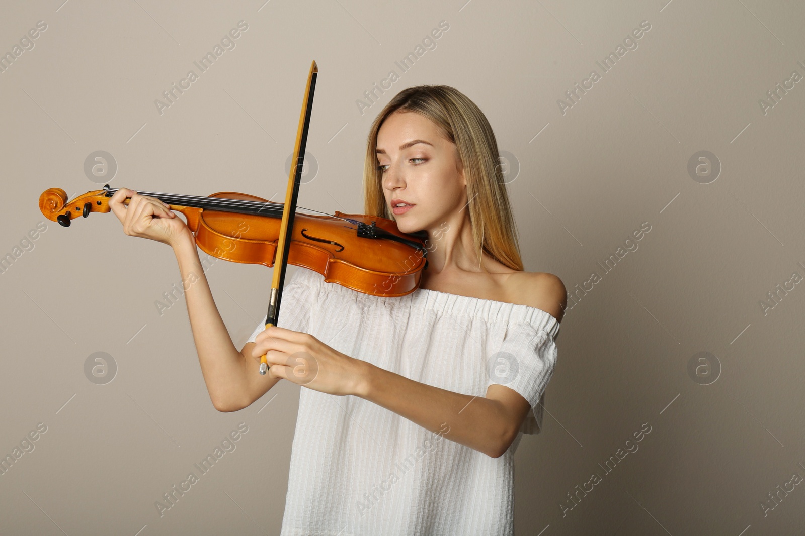 Photo of Beautiful woman playing violin on beige background