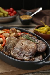 Photo of Tasty beef tongue pieces with potatoes, pepper and rosemary on wooden board
