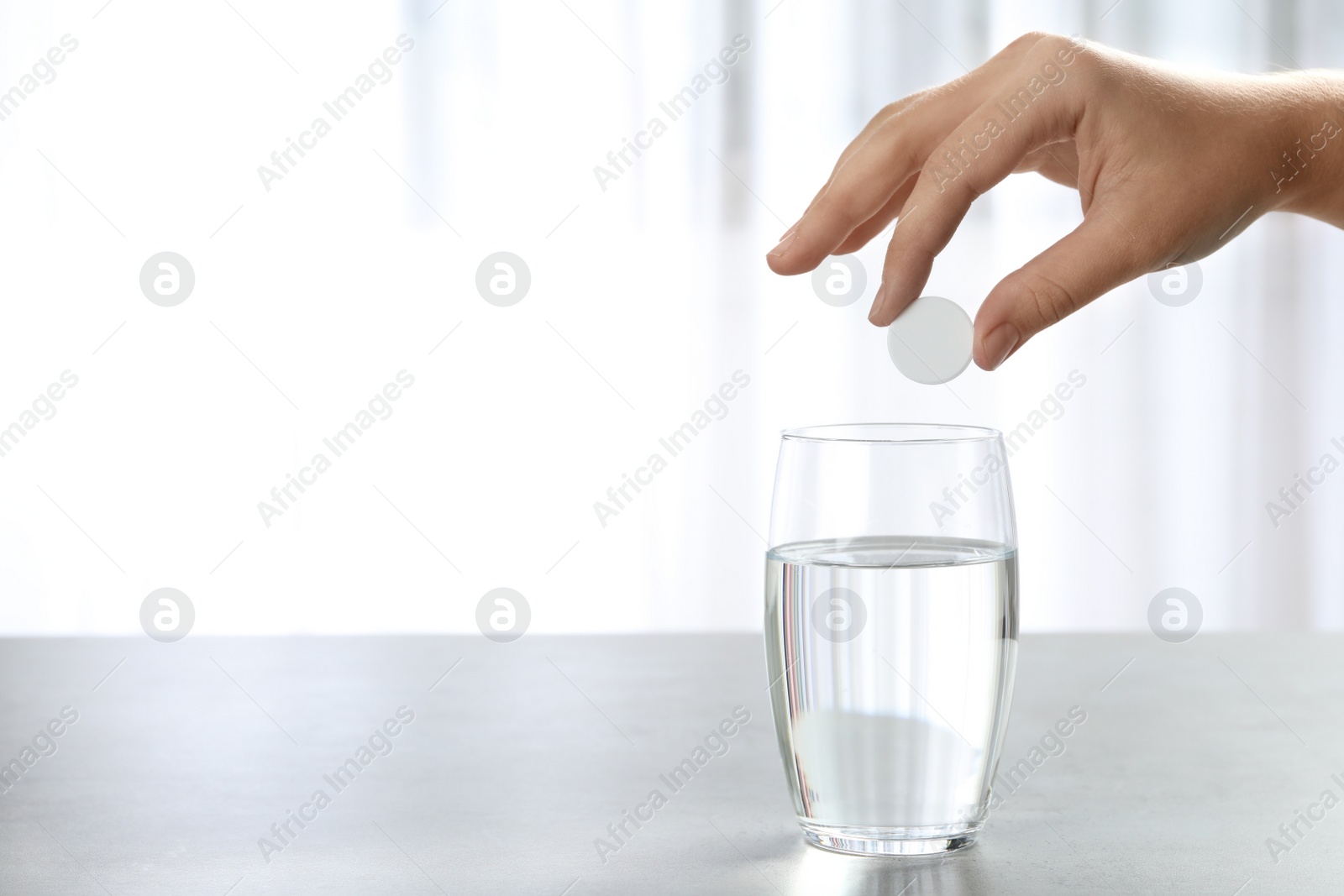 Photo of Woman putting tablet into glass of water indoors, space for text