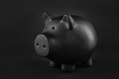 Photo of Black piggy bank on table against dark background