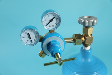 Photo of Pressure gauge of medical oxygen tank on light blue background, closeup