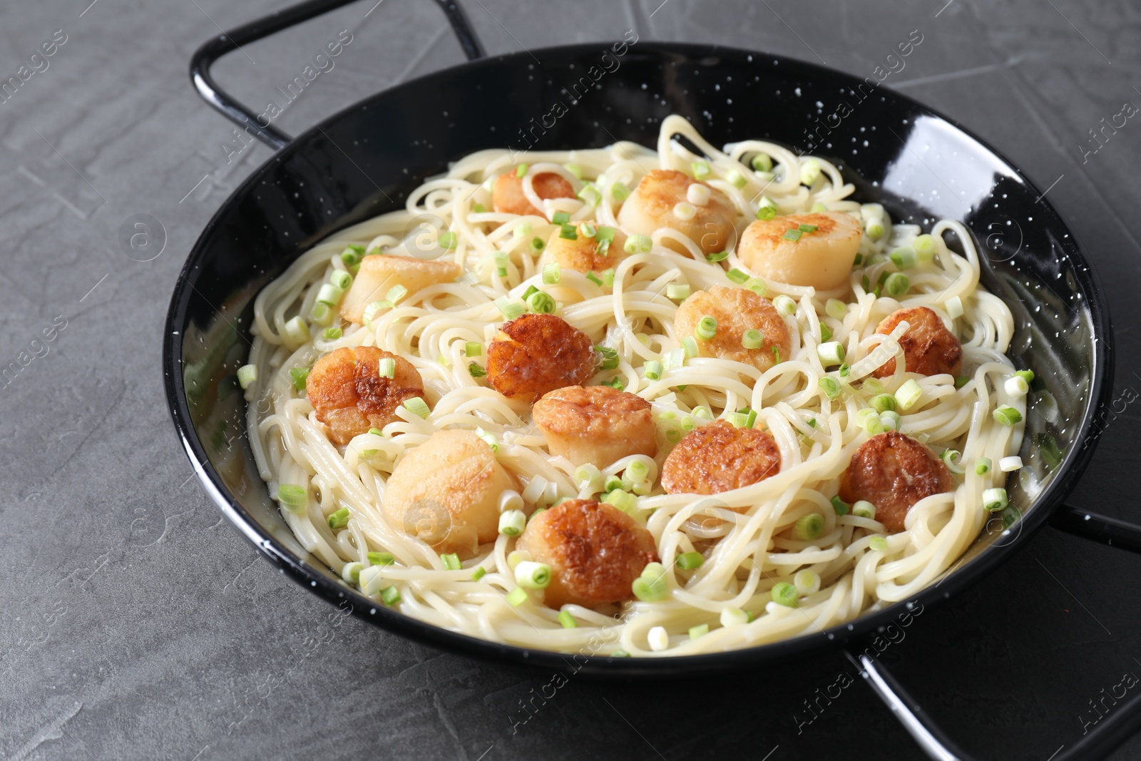 Photo of Delicious scallop pasta with green onion on grey table, closeup