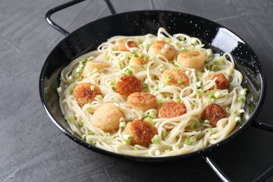 Photo of Delicious scallop pasta with green onion on grey table, closeup