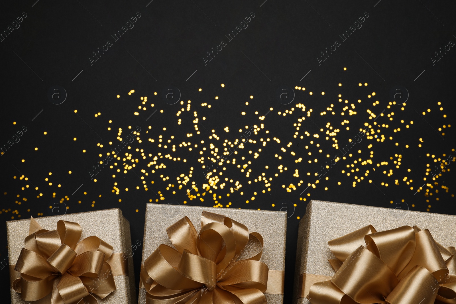 Photo of Golden gift boxes and confetti on black background, flat lay. Space for text