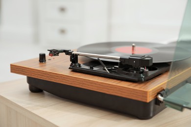 Photo of Turntable with vinyl record on table against blurred background, closeup