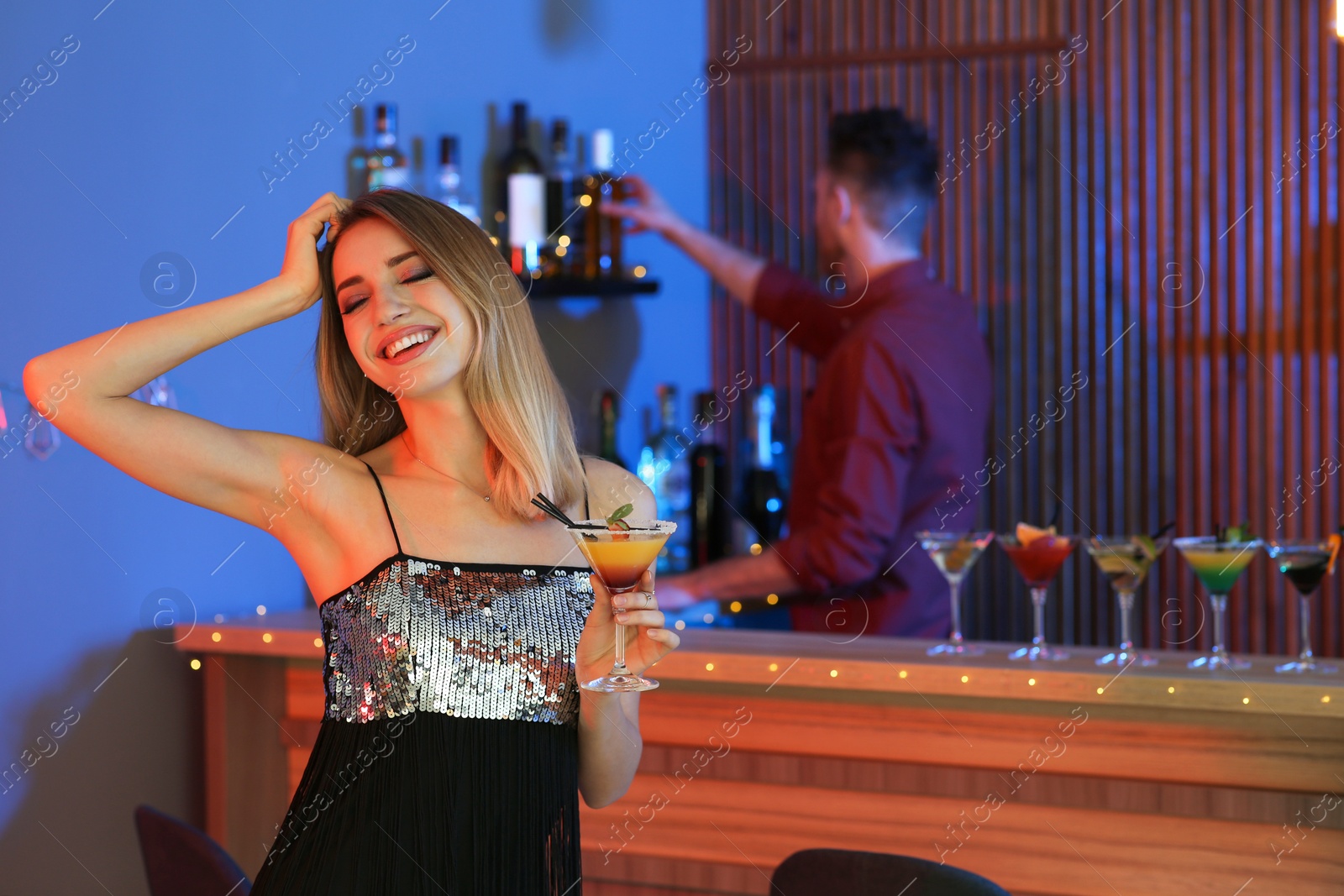 Photo of Beautiful young woman with glass of martini cocktail in bar, space for text