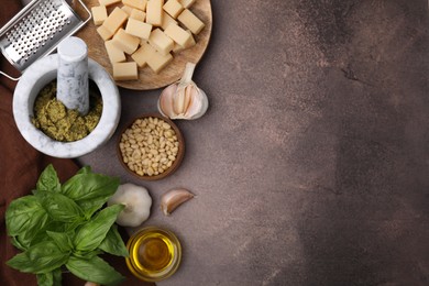 Photo of Tasty pesto sauce and ingredients on brown textured table, flat lay. Space for text