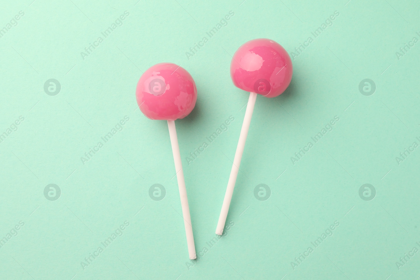 Photo of Tasty lollipops on turquoise background, flat lay