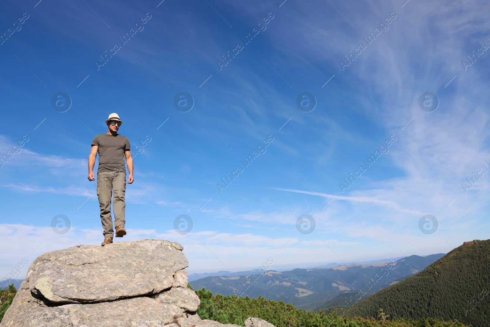 Photo of Man enjoying picturesque view on cliff in mountains. Space for text