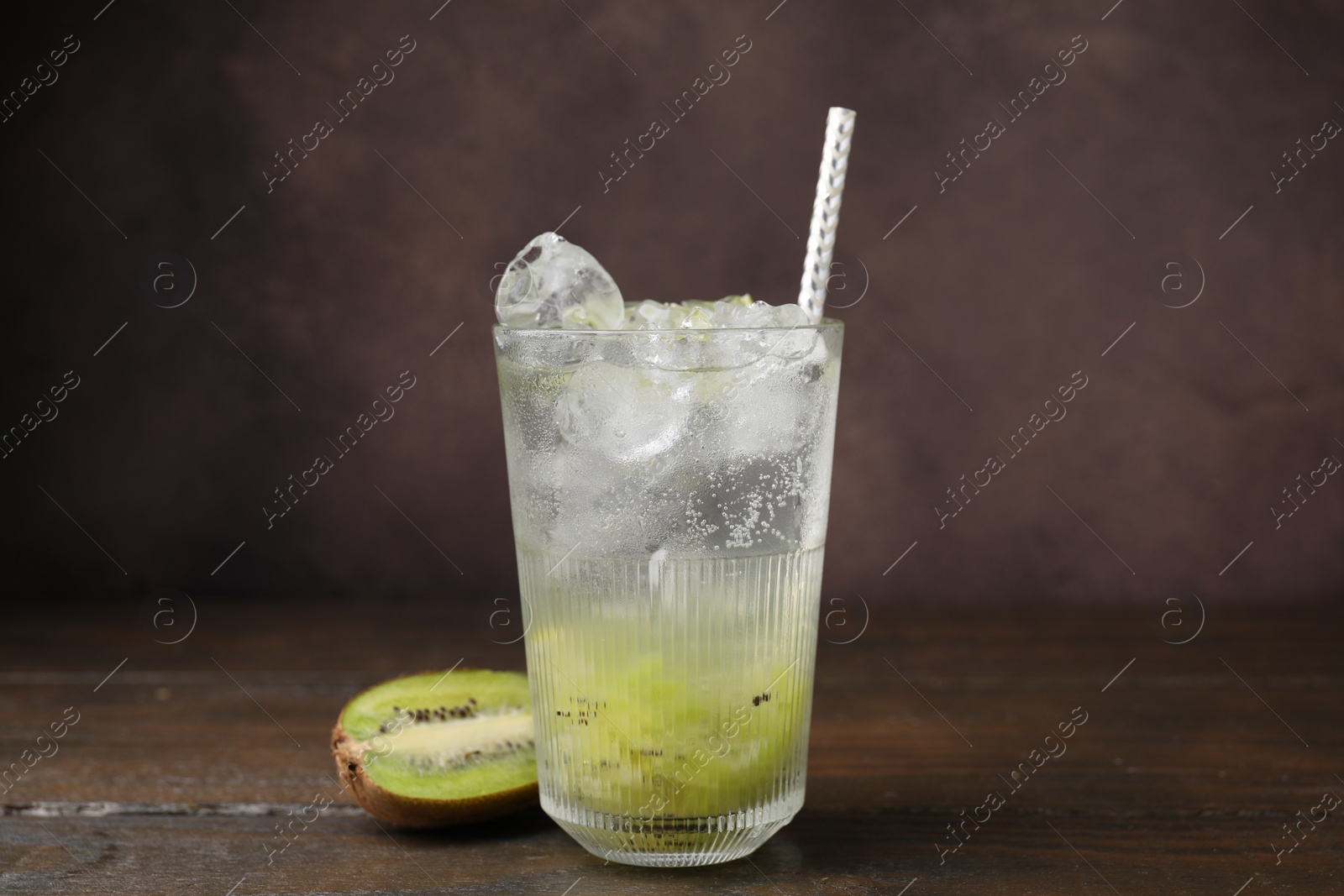 Photo of Glass of refreshing drink and cut kiwi on wooden table