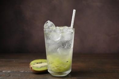 Glass of refreshing drink and cut kiwi on wooden table