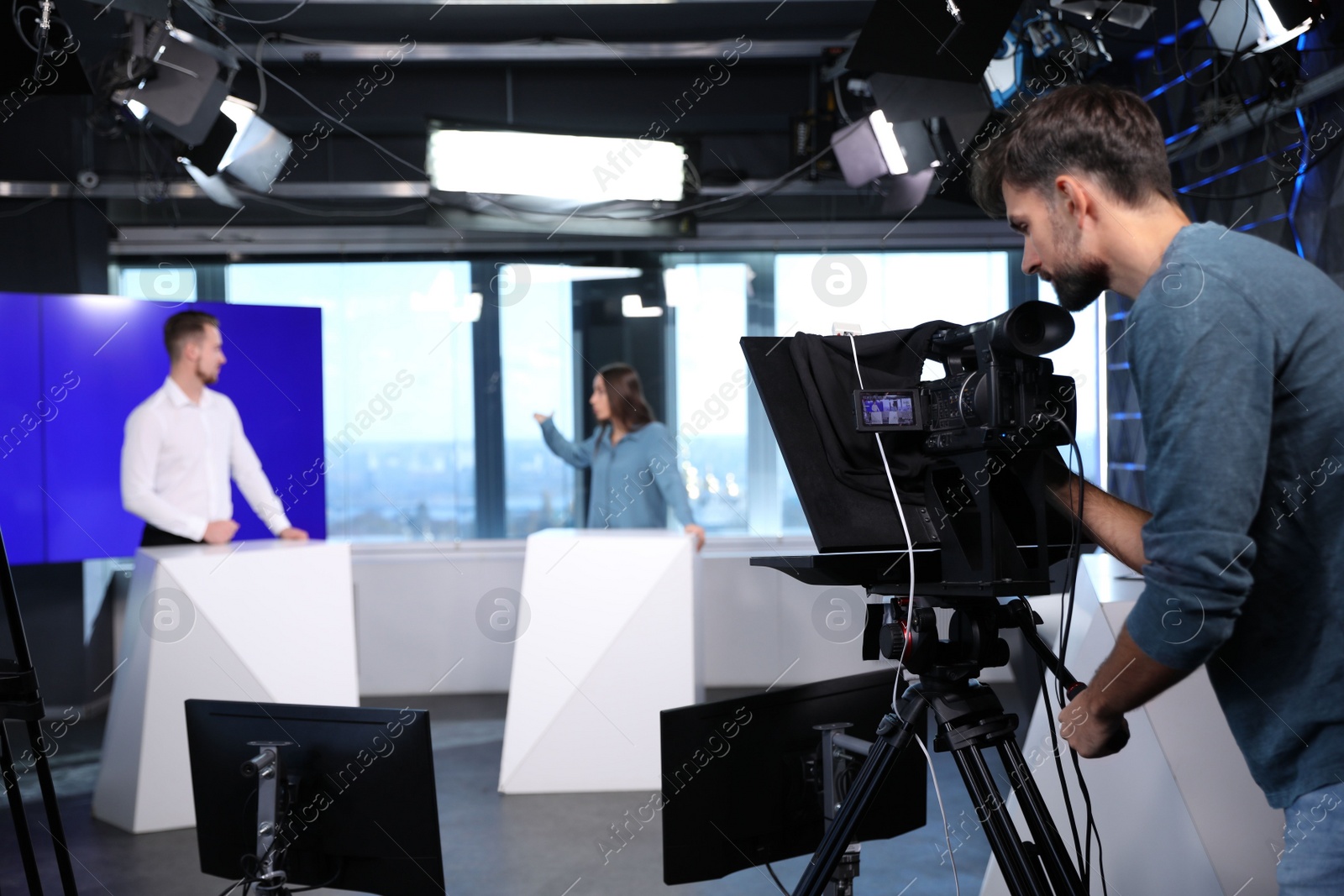 Photo of Presenters and video camera operator working in studio. News broadcasting