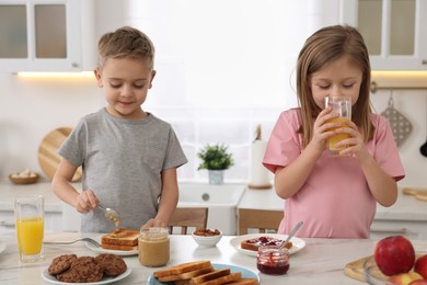 Photo of Little children having breakfast at table in kitchen
