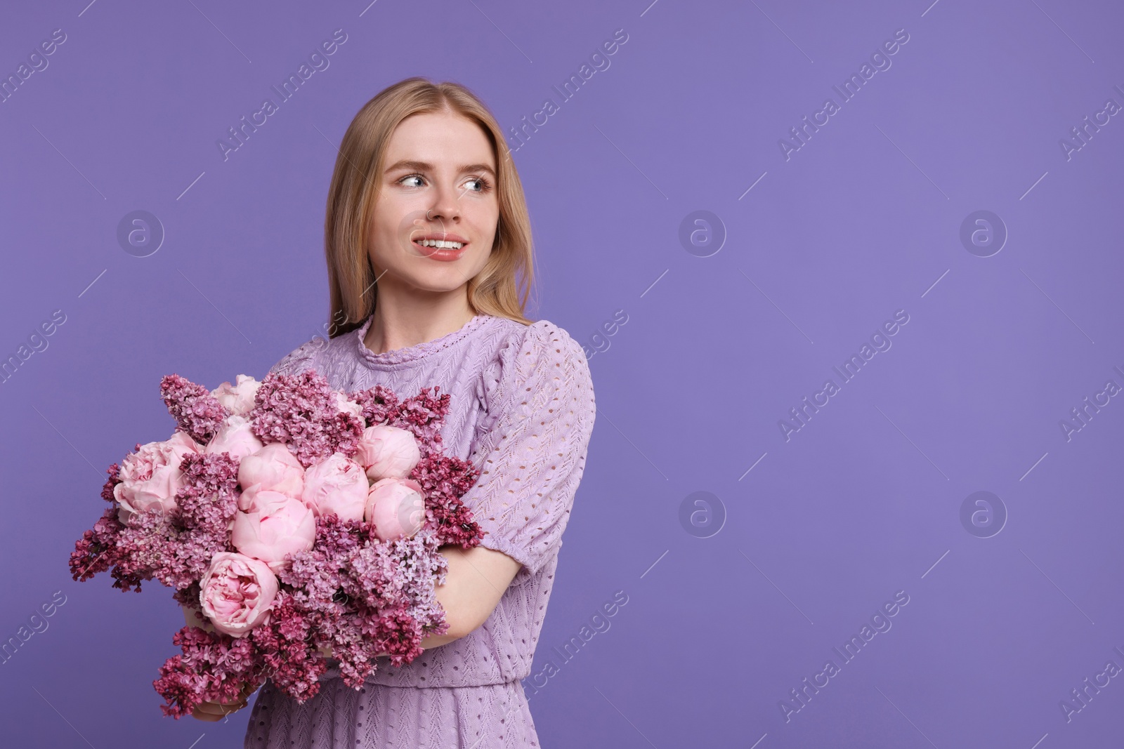 Photo of Beautiful woman with bouquet of spring flowers on purple background, space for text