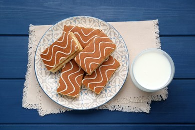 Photo of Tasty sponge cakes and milk on blue wooden table, flat lay