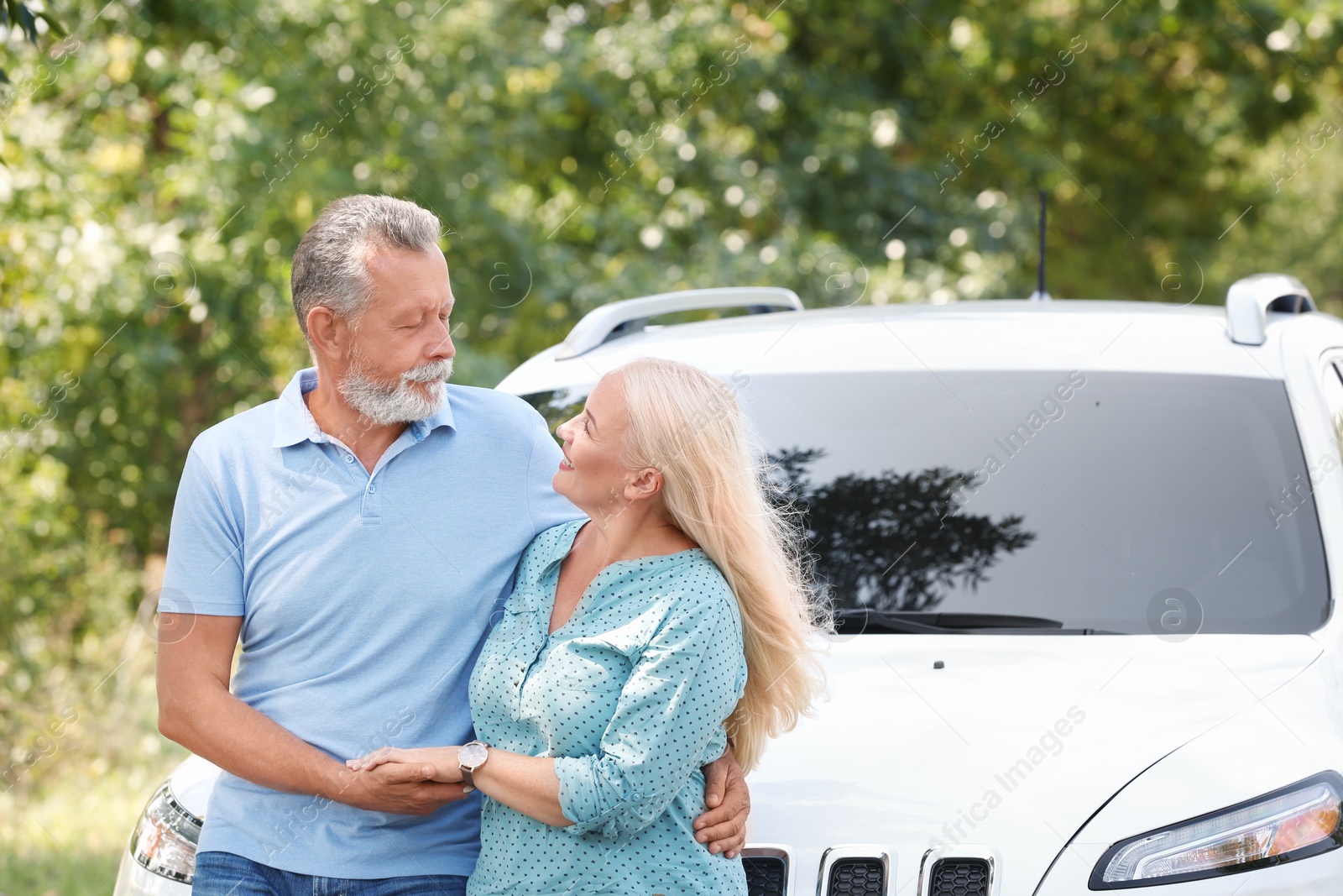 Photo of Happy senior couple posing near car outdoors