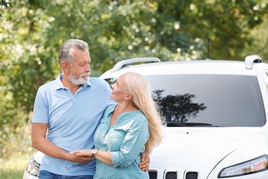 Photo of Happy senior couple posing near car outdoors