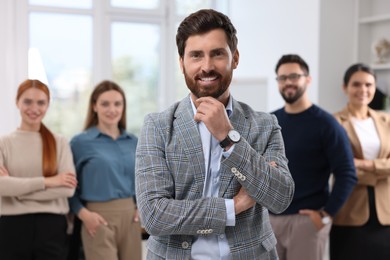 Photo of Portrait of happy businessman and his team in office