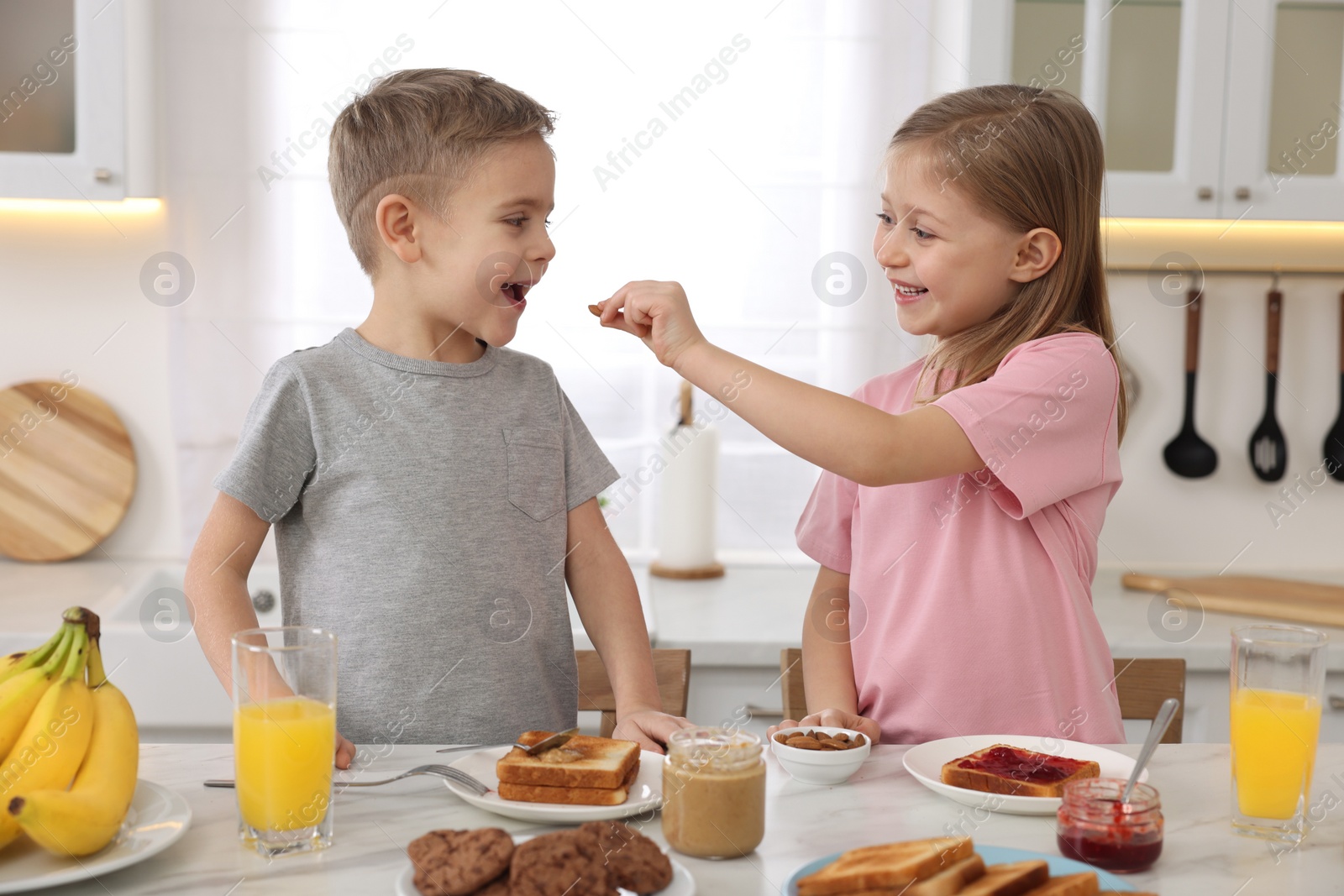 Photo of Little children having fun during breakfast at table in kitchen