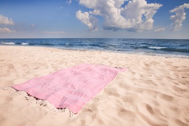 Pink striped beach towel on sandy seashore