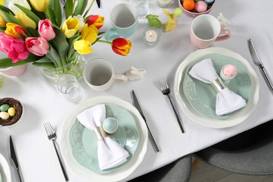 Festive Easter table setting with beautiful flowers and painted eggs, top view