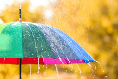 Photo of Bright color umbrella under rain outdoors, closeup