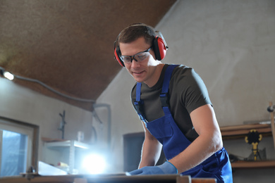 Professional carpenter working with wood in shop