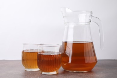 Homemade fermented kombucha in glasses and jug on grey table