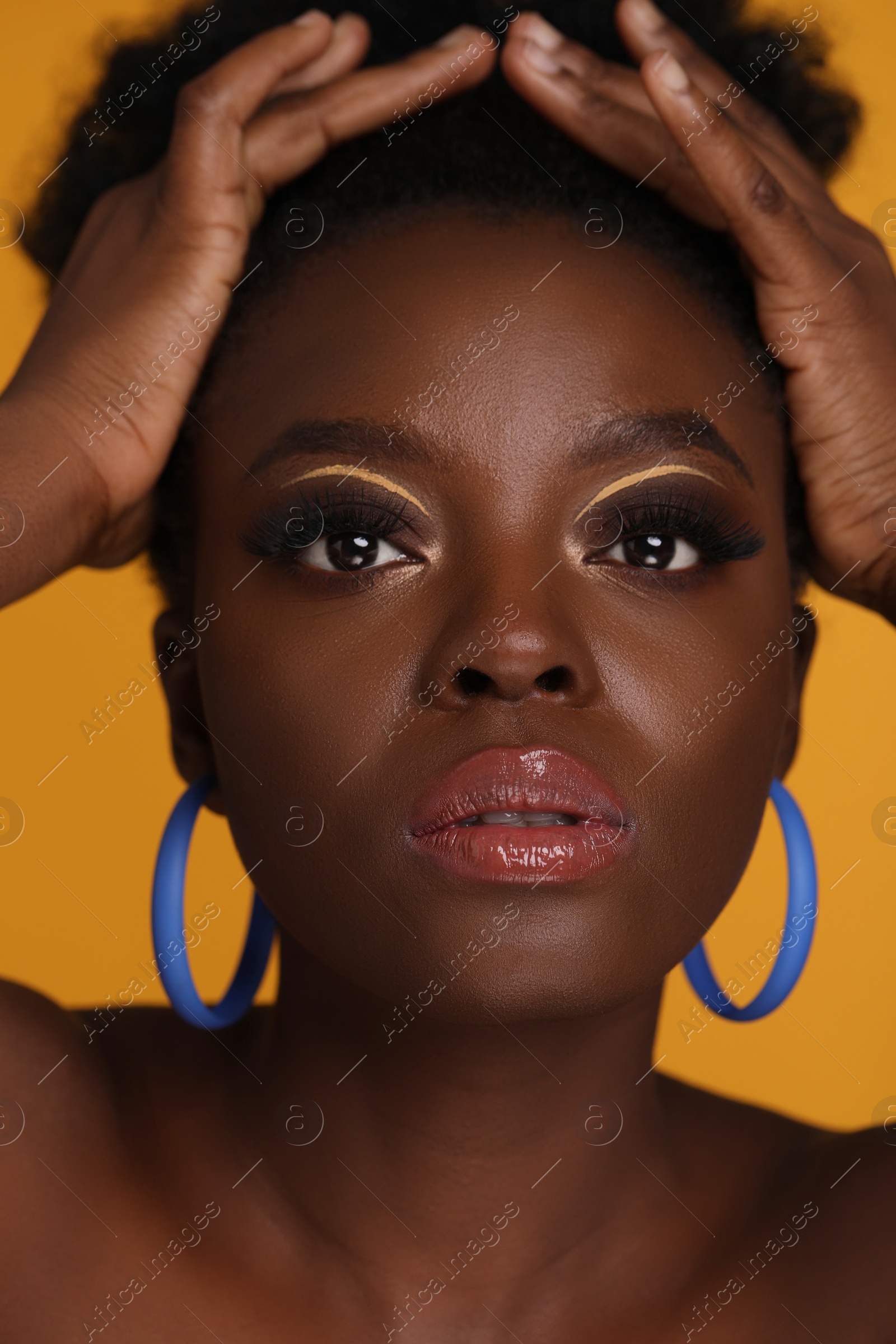 Photo of Fashionable portrait of beautiful woman with makeup on orange background, closeup