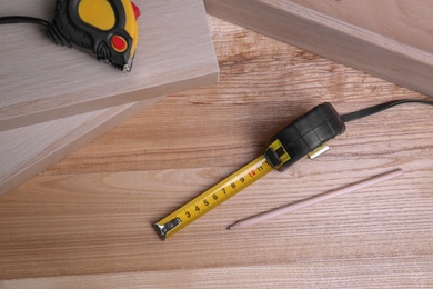 Photo of Tape measure and pencil on wooden surface, above view