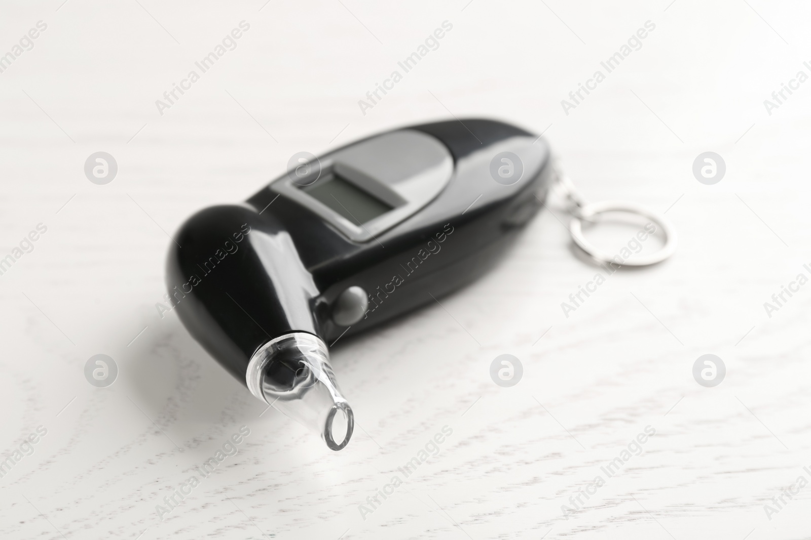 Photo of Modern breathalyzer with mouthpiece on white wooden table, closeup