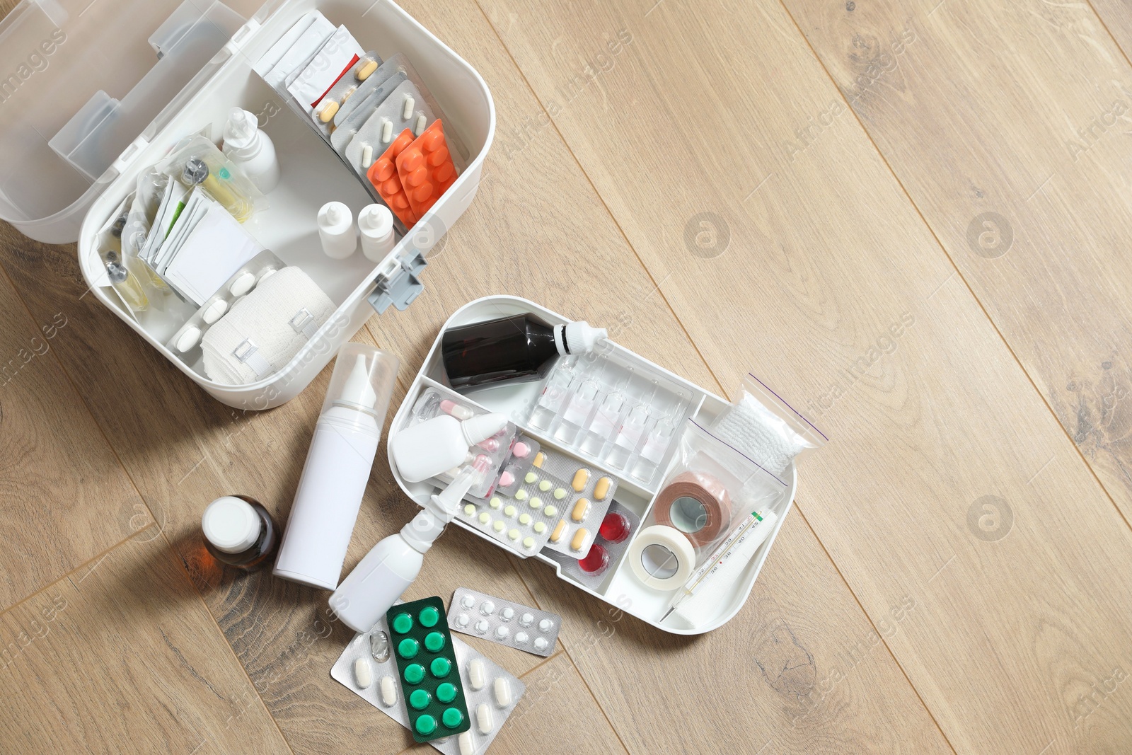 Photo of First aid kit and medicaments on floor indoors, flat lay. Space for text